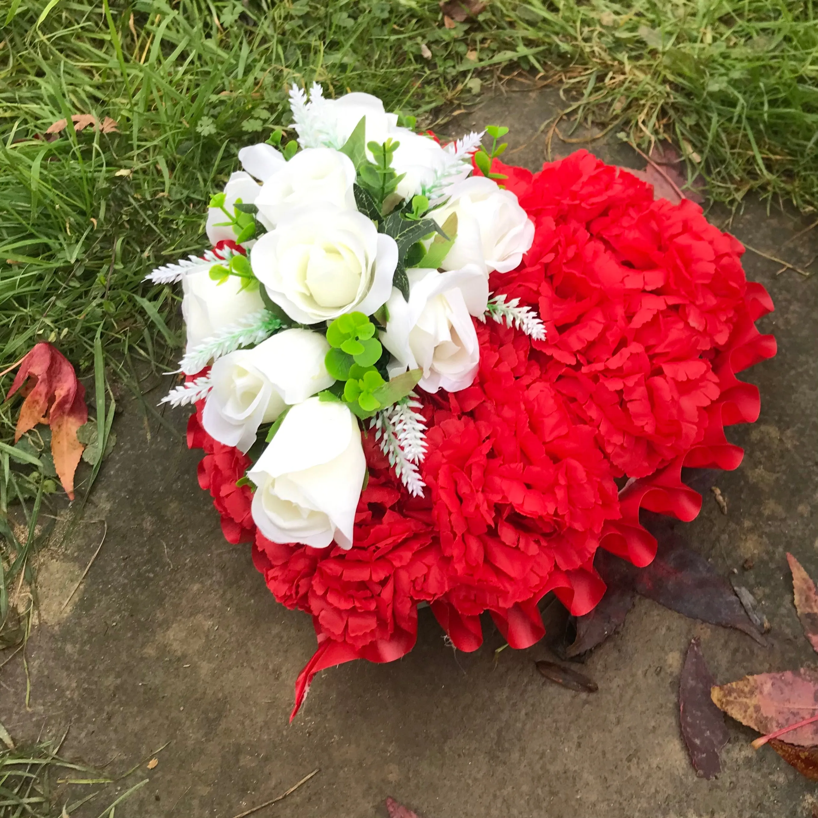 a based memorial heart of artificial silk roses & carnations in shades of red & white