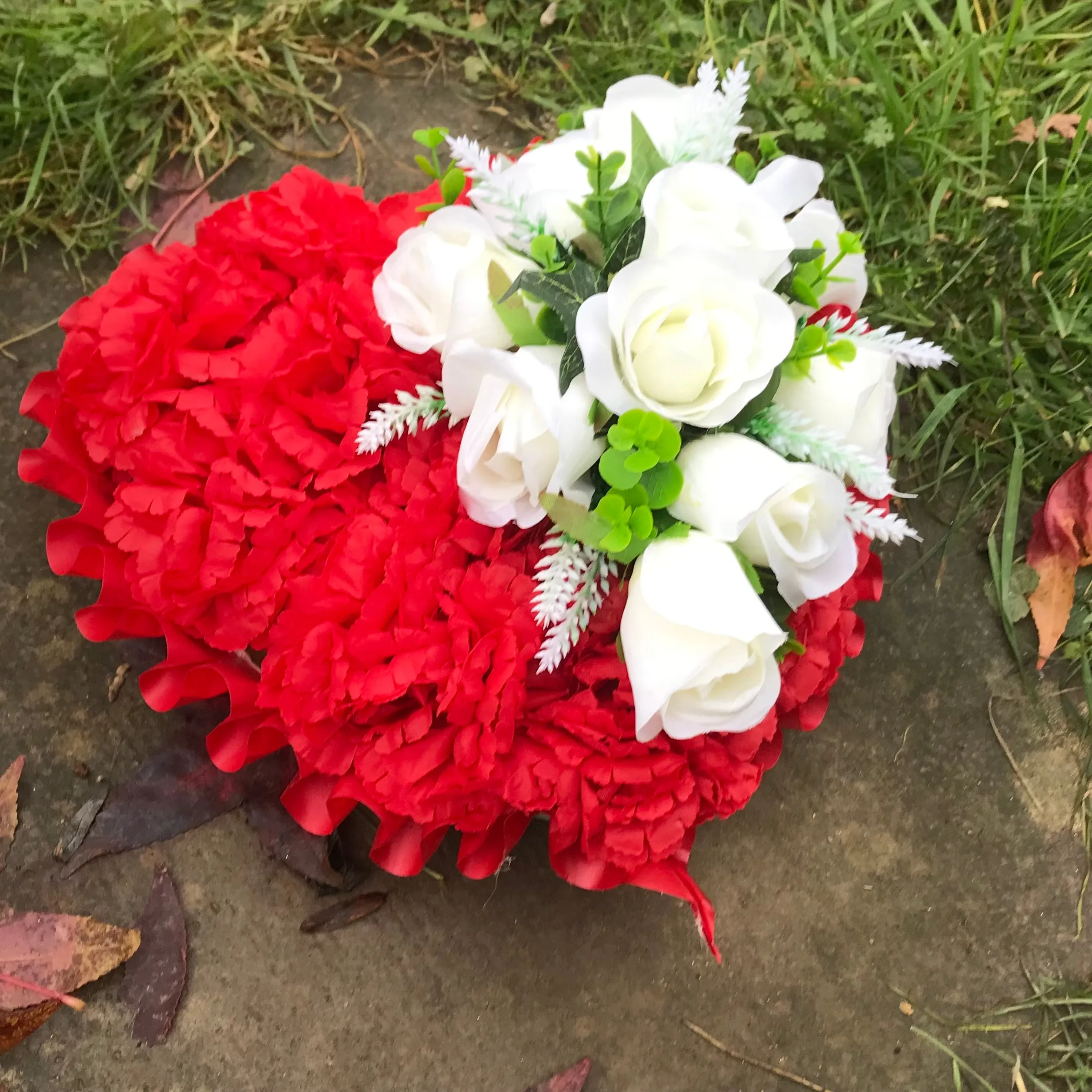 a based memorial heart of artificial silk roses & carnations in shades of red & white