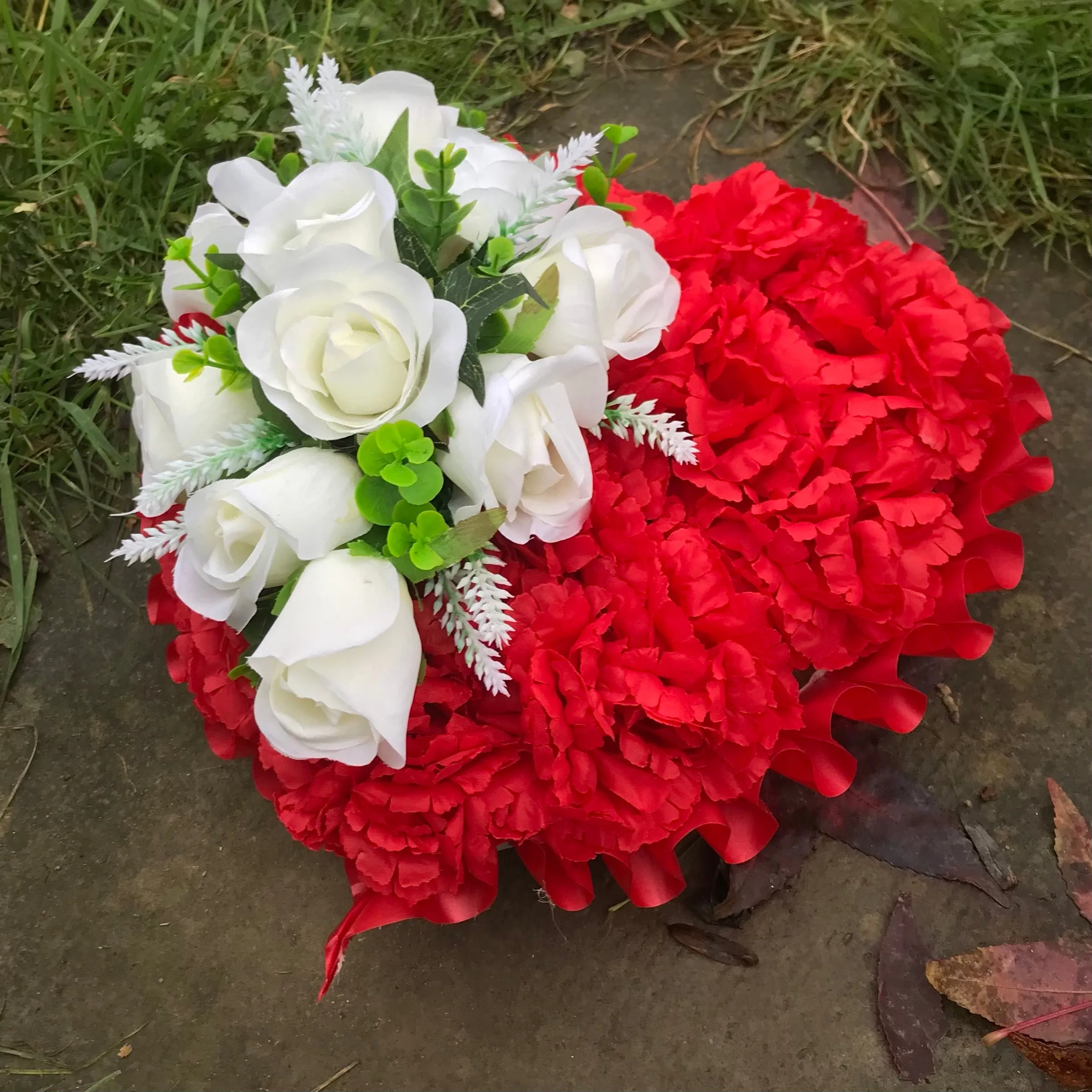 a based memorial heart of artificial silk roses & carnations in shades of red & white