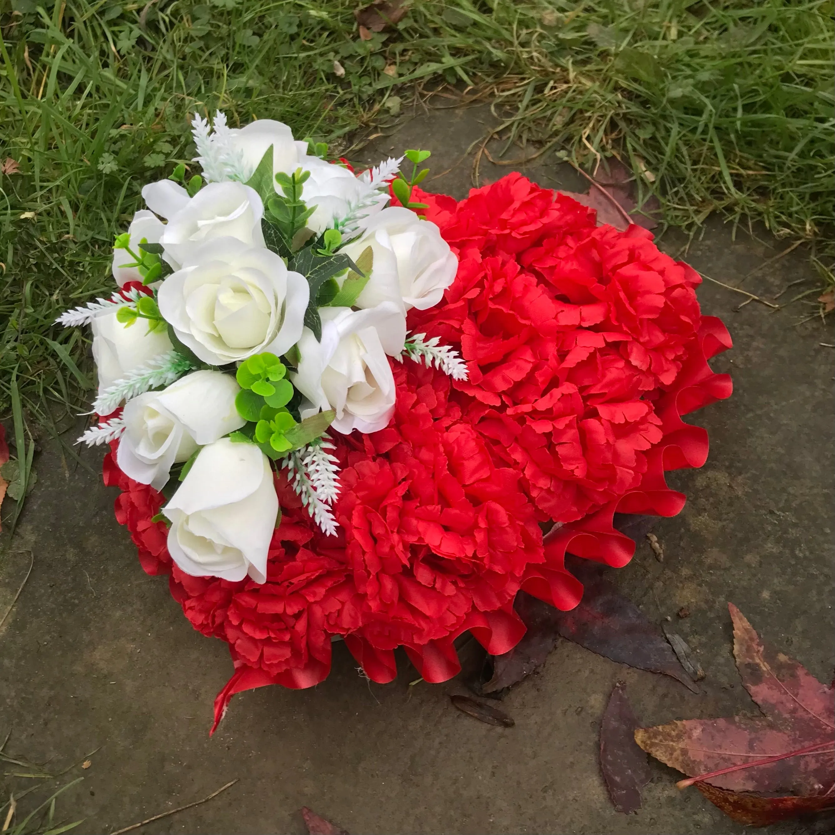 a based memorial heart of artificial silk roses & carnations in shades of red & white