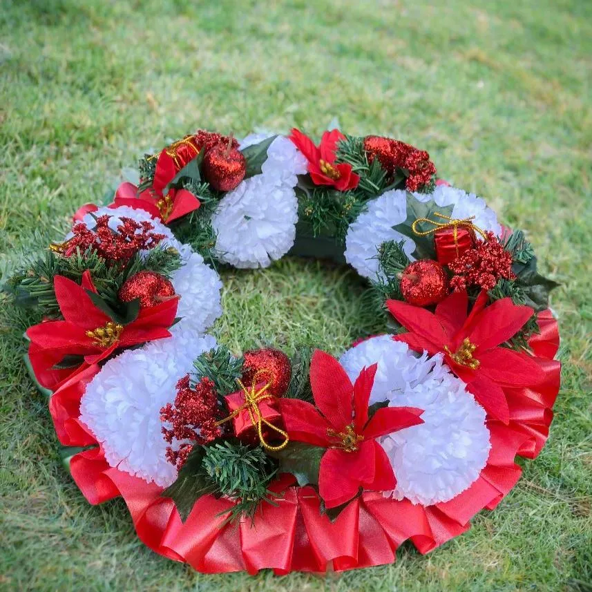 a memorial christmas wreath featuring baubles, cones and poinsettia